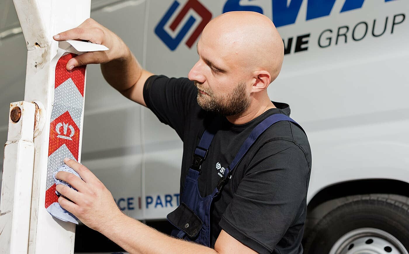Mann klebt Reflektion auf einen Poller